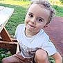 child, toddler, portrait, outdoor, park, picnic_table, bench, grass, curly_hair, smile, sandals, white_tshirt, shorts, face, big_eyes, playful, candid, nature, happy, sitting