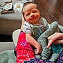 Luca joined the competition — help win amazing prizes! baby, infant, person, arm, blanket, clothing, hand, pacifier, red_sleeve, knitted_blanket, wooden_floor, table, bottle, book, face, smile, indoors, holding, cozy, home