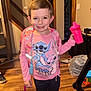 child, smiling, indoor, backpack, pink, sippy_cup, stitch, cartoon_clothing, long_sleeve_shirt, pants, wooden_floor, home, doorway, stairs, toy, person, happy, casual, standing, young_child