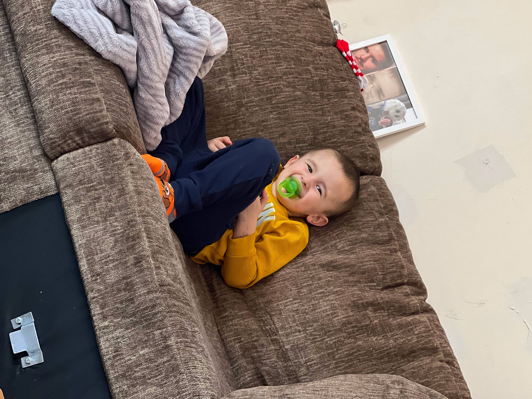 Logan is registered to the contest to win money with this photo: baby, bedding, child, comfort, couch, flooring, grey, house, leisure, linens, nap, person, room, sitting, sleep, sleeve, t_shirt, throw_pillow, toddler, wall