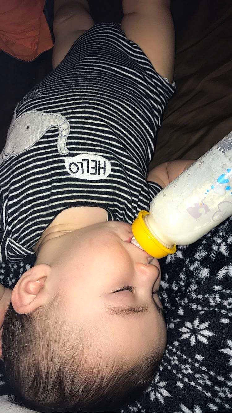 Logan is registered to the contest to win money with this photo: baby_bottle, beard, black_hair, drinking, drinkware, eyelash, finger, fluid, gesture, human_body, mouth, nail, neck, nose, organ, person, plastic_bottle, skin, thigh, thumb