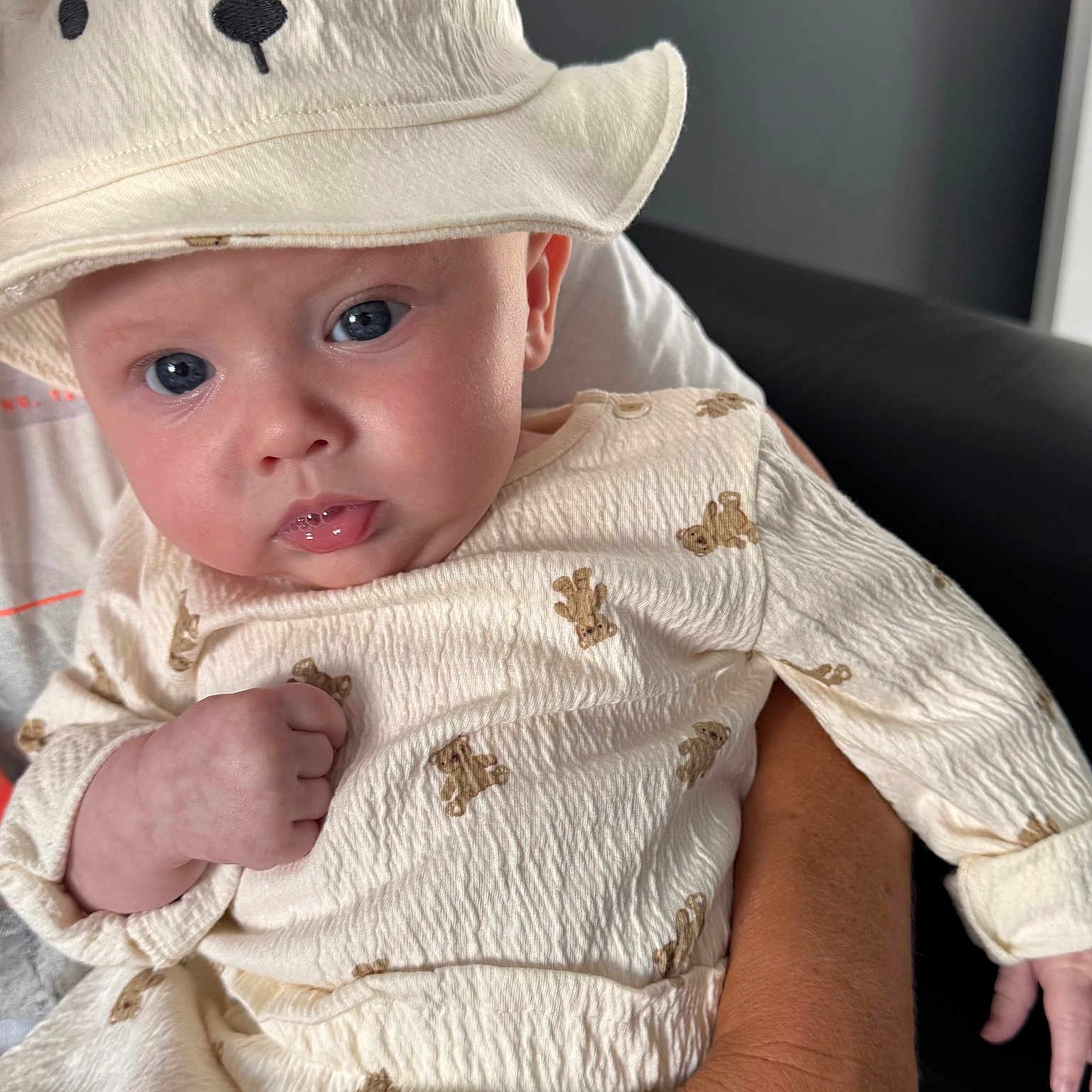 Jude joined the competition — help win amazing prizes! adult, baby, bear, blue_eyes, clothing, cozy, cute, expression, face, hand, hat, holding, indoor, infant, person, portrait, sitting, skin, soft_texture, white