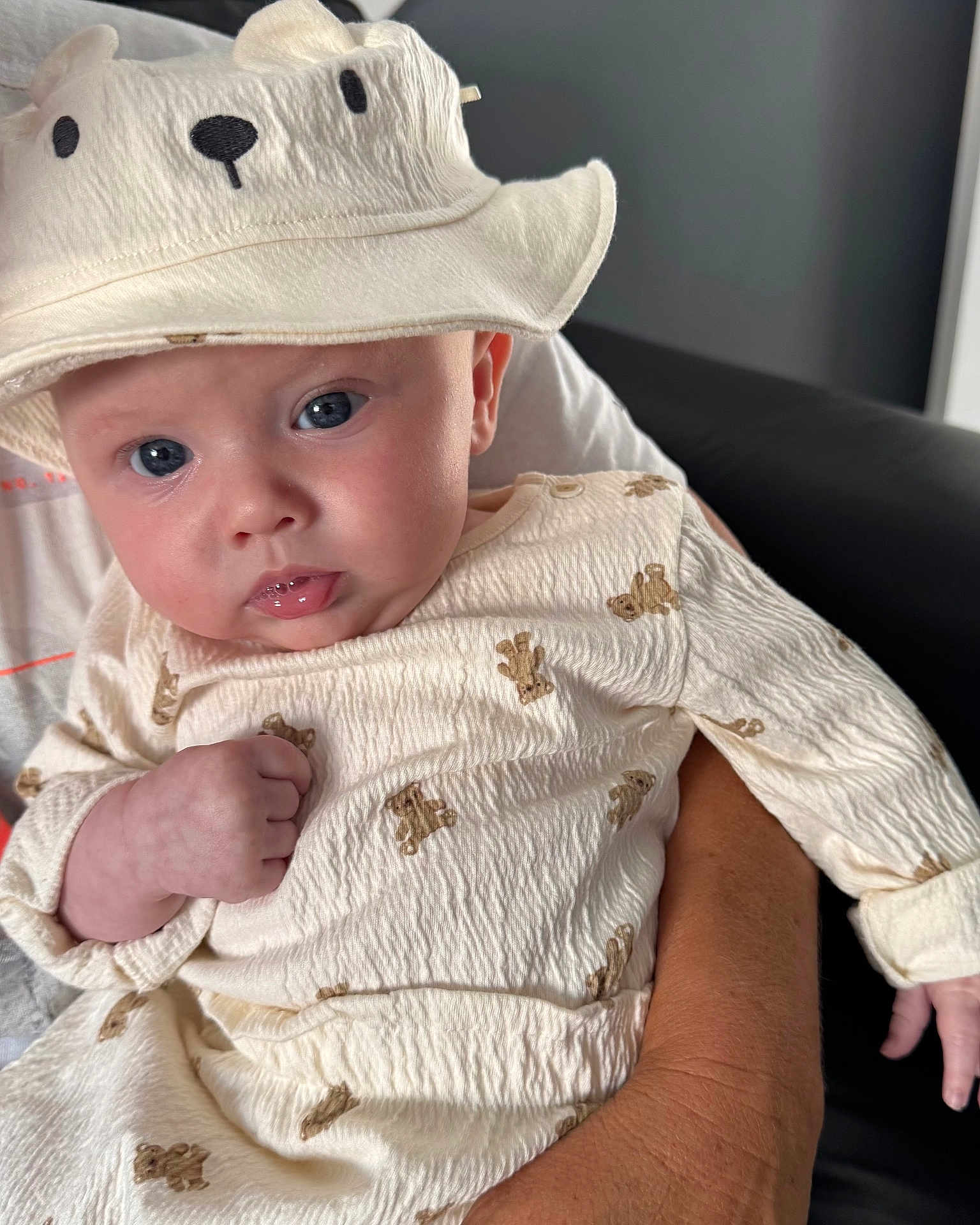 Jude joined the competition — help win amazing prizes! baby, infant, hat, bear, clothing, cute, face, person, hand, adult, skin, blue_eyes, sitting, holding, indoor, portrait, expression, soft_texture, white, cozy