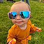cheese_puffs, child, cute, event, face, fashion, fun, grass, hand, orange_clothing, outdoor, people, playful, portrait, reflection, smile, snack, sunglasses, sunlight, toddler