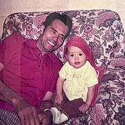 Cleopatra is registered to the contest to win money with this photo: man, baby, child, smile, red_shirt, red_hat, floral_couch, vintage_photo, indoor, portrait, sitting, family, happy, people, pattern, fabric, casual, retro, candid, home