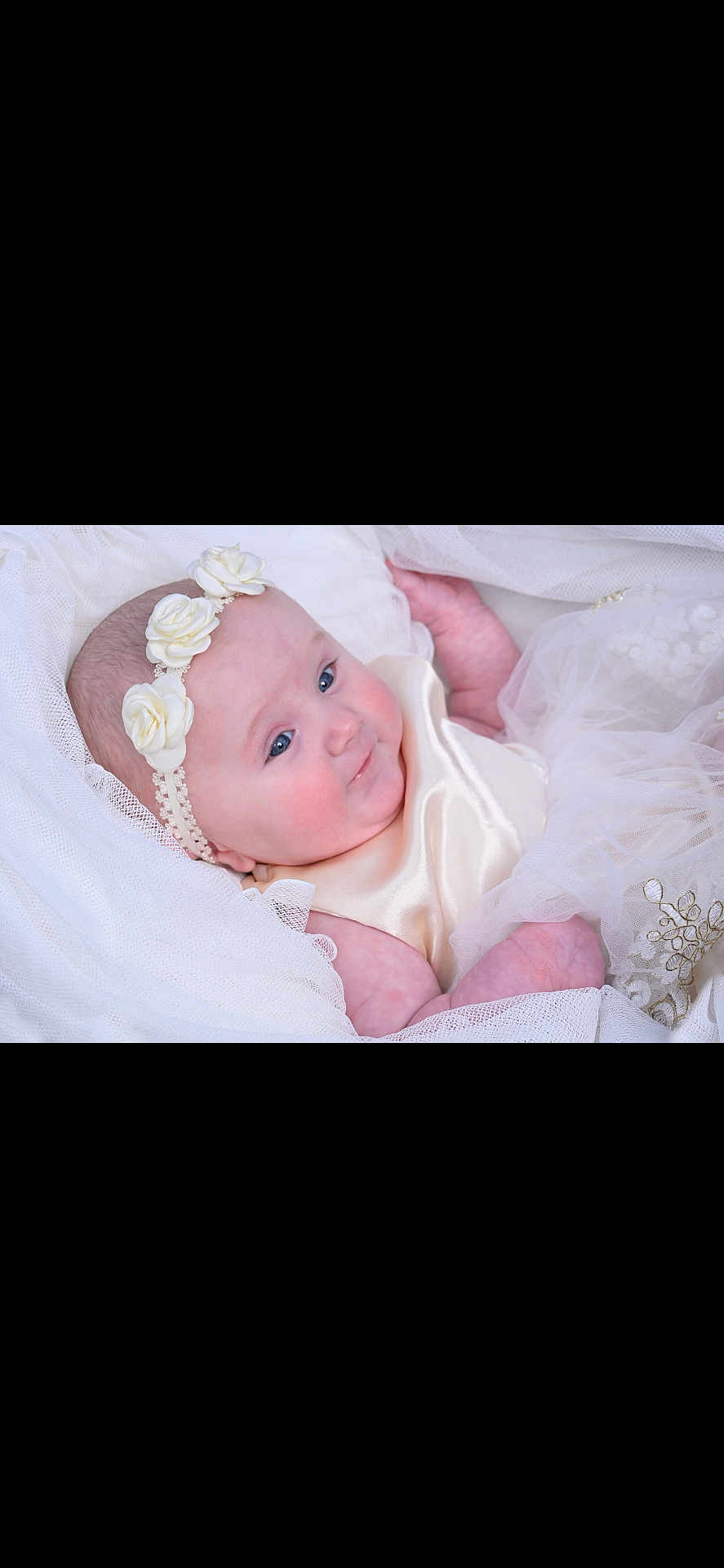 Charlotte is registered to the contest to win money with this photo: baby, infant, headband, flower, white_clothing, silk, soft_fabric, portrait, cute, child, newborn, smile, blue_eyes, skin, lying_down, delicate, tulle, dress, baby_girl, closeup