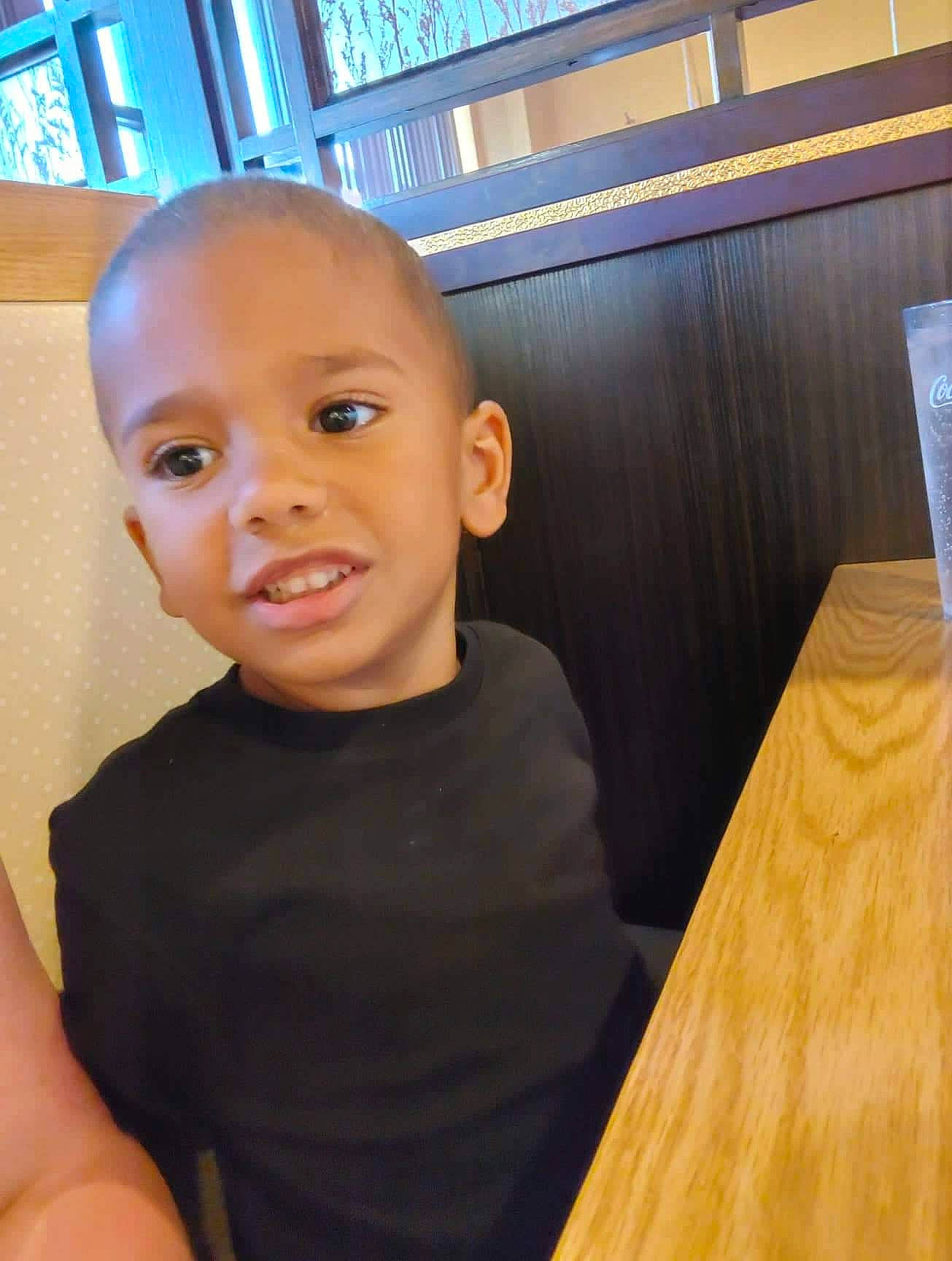 Bradley is registered to the contest to win money with this photo: cheek, chest, child, flooring, fun, happy, hardwood, nose, person, plywood, room, sitting, smile, standing, t_shirt, table, thumb, toddler, varnish, wood