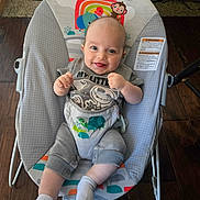 Elijah joined the competition — help win amazing prizes! baby, infant, smiling, baby_rocker, clothing, socks, floor, wooden_floor, happy, cute, indoor, person, child, seat, toddler, toy_pattern, colorful, face, expression, comfort