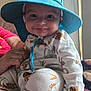 baby, child, smile, hat, blue_hat, pajamas, animal_print, hand, indoor, natural_light, person, face, cute, infant, clothing, sitting, closeup, cozy, happy, portrait