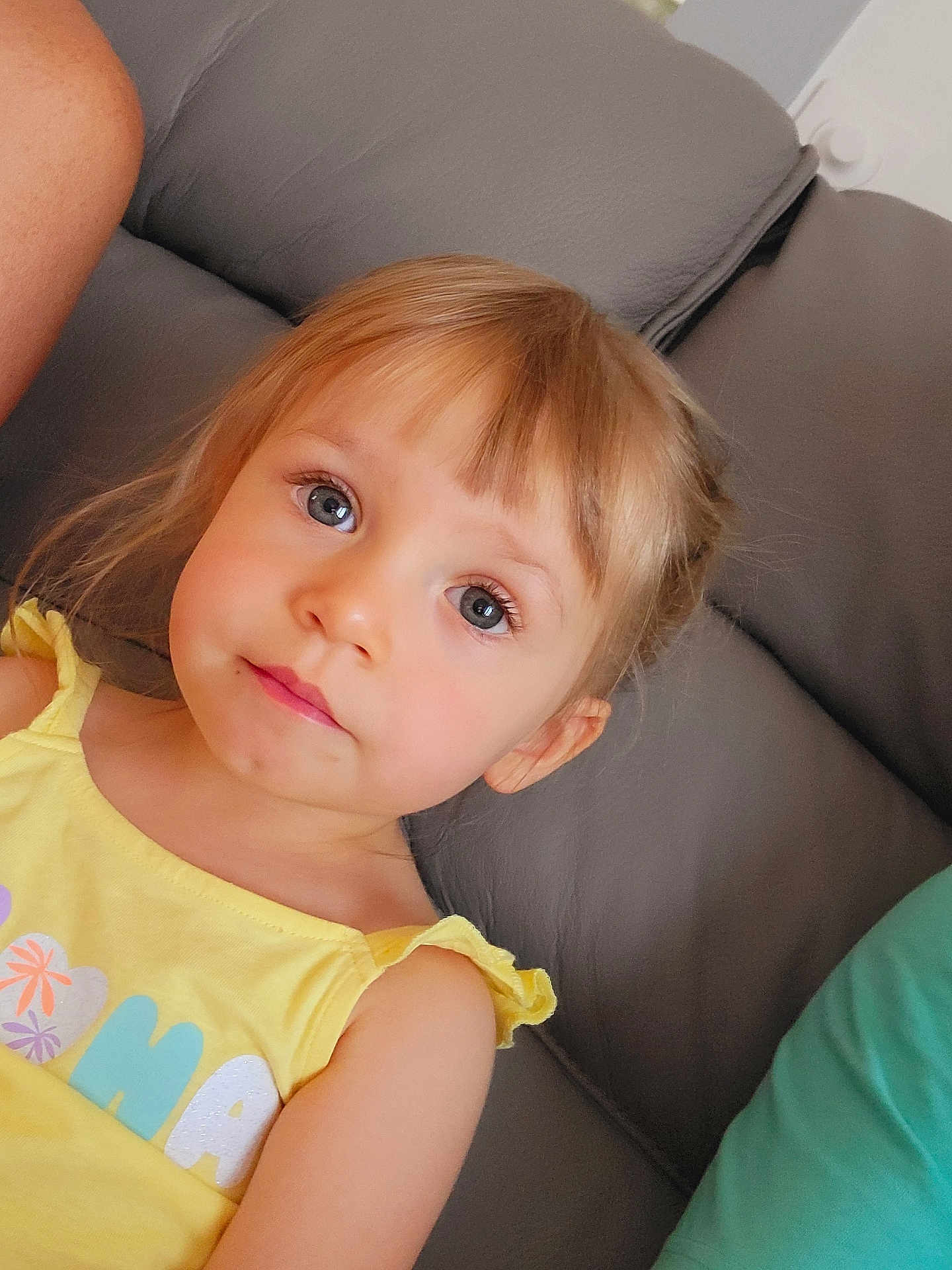Amalya participe au concours pour gagner de l'argent avec cette photo : child, portrait, face, blonde_hair, blue_eyes, yellow_clothing, sitting, couch, indoor, person, young, cute, casual, relaxed, closeup, natural_light, home, furniture, expression, soft