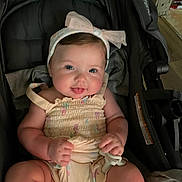Annabella is registered to the contest to win money with this photo: baby, infant, smiling, headband, romper, stroller, child, cute, chubby, indoors, person, happy, face, legs, hands, sitting, clothing, accessory, babygear, soft