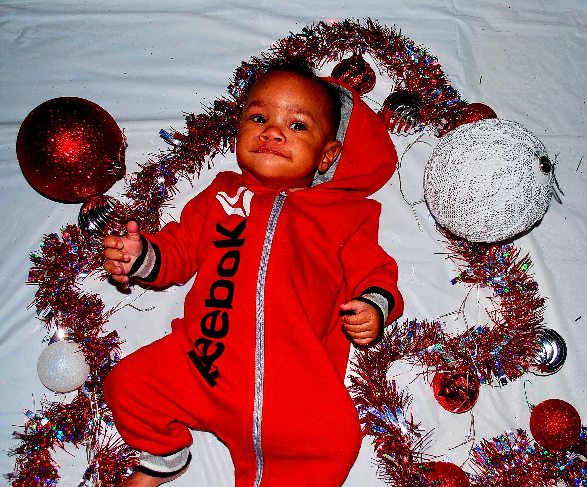 Asher is registered to the contest to win money with this photo: baby_toddler_clothing, child, christmas, christmas_decoration, christmas_eve, christmas_ornament, decoration, event, facial_expression, fun, gesture, happy, holiday, holiday_ornament, ornament, people_in_nature, person, red, sleeve, toddler