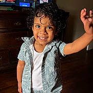 King joined the competition — help win amazing prizes! child, toddler, curly_hair, smiling, waving, indoor, wooden_floor, dresser, television, casual_clothing, patterned_outfit, happy, cute, portrait, person, young_child, living_room, home, bright, playful