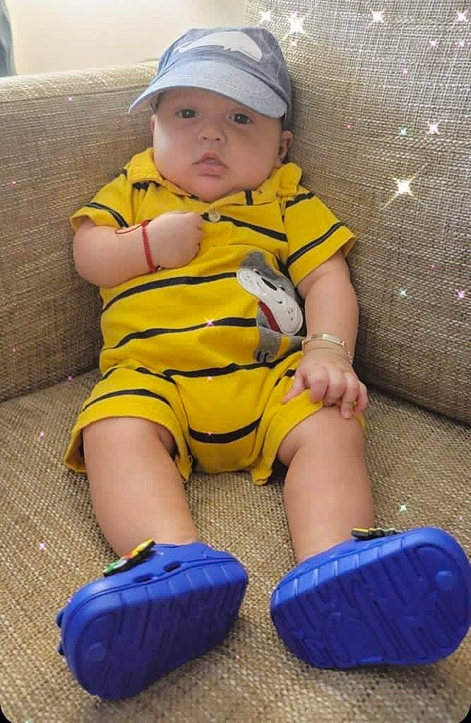 Hector is registered to the contest to win money with this photo: baby, baby_toddler_clothing, baseball_cap, cap, child, comfort, electric_blue, face, foot, fun, head, headwear, human_leg, knee, pattern, person, skin, sleeve, sock, thigh