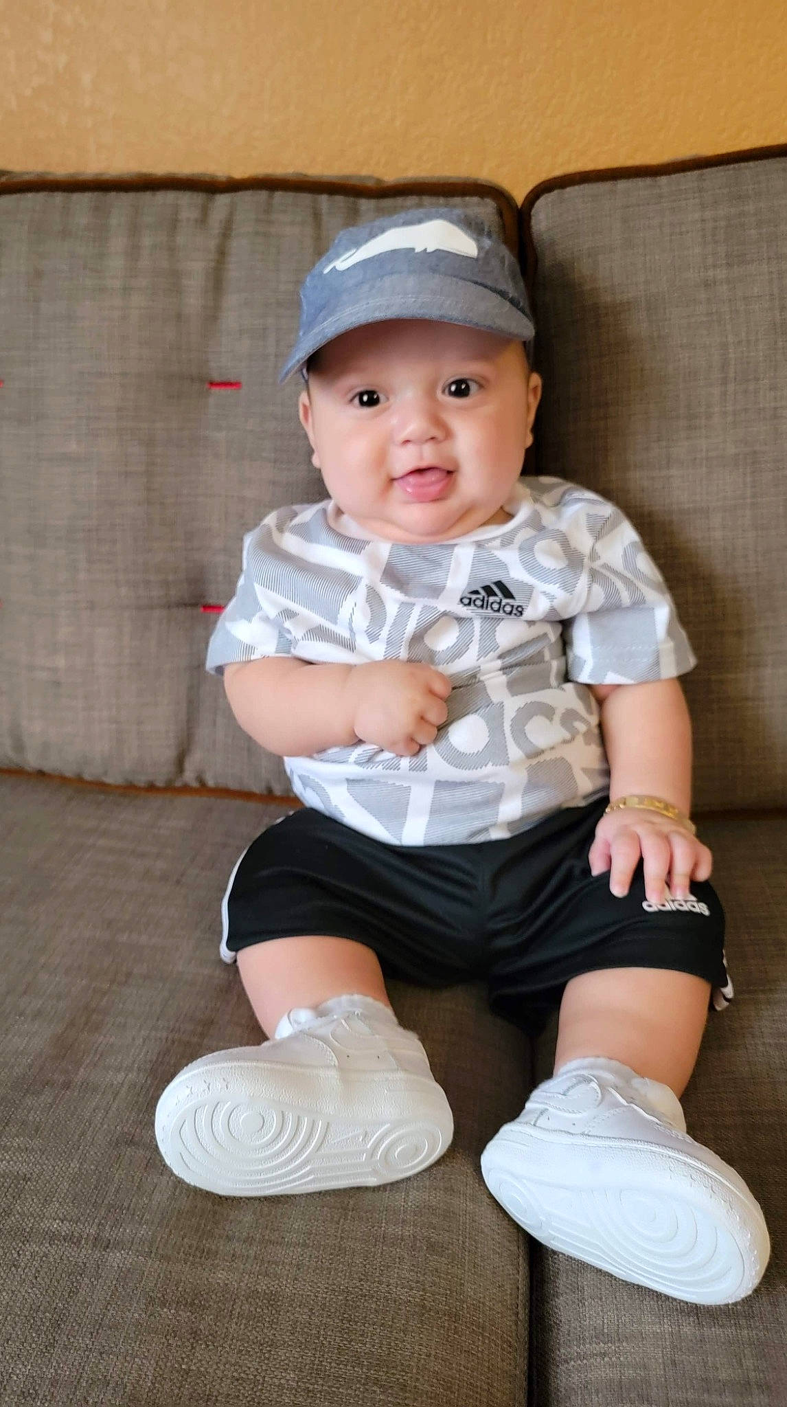 Hector is registered to the contest to win money with this photo: arm, baby, baby_toddler_clothing, cap, child, cool, fashion_accessory, flash_photography, headwear, human_leg, knee, leg, pattern, person, shorts, sitting, skin, sleeve, sock, t_shirt