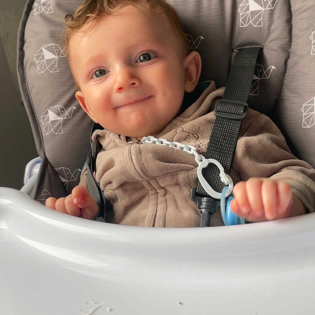 Kézyo participe au concours pour gagner de l'argent avec cette photo : baby, baby_clothes, child, closeup, clothing, cute, elephant_pattern, face, hand, happy, high_chair, indoor, infant, pacifier, portrait, seatbelt, sitting, smile, toy, young_child
