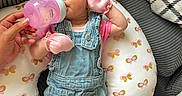 Lily is registered to the contest to win money with this photo: baby, bottle, butterfly_pattern, child, comfortable, couch, cute, denim_overalls, feeding, hand, headband, home, indoor, infant, person, pillow, pink_mittens, relaxed, socks, soft_lighting