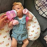 Lily is registered to the contest to win money with this photo: baby, infant, bottle, feeding, headband, denim_overalls, pink_mittens, socks, couch, pillow, butterfly_pattern, hand, indoor, child, cute, relaxed, soft_lighting, person, comfortable, home