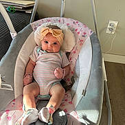 Lily is registered to the contest to win money with this photo: baby, baby_swing, child, comfort, cushion, cute, floor, floral_pattern, headband, indoor, infant, mittens, onesie, person, plug_socket, portrait, seated, socks, soft_toys, sunlight