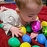 Niklaus is registered to the contest to win money with this photo: baby, blanket, bright_colors, child, closeup, colorful, crawling, curious, easter_eggs, face, floor, hands, head, indoor, infant, plastic_eggs, play, red_blanket, toys, young_child