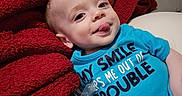 Niklaus joined the competition — help win amazing prizes! baby, blanket, blue_shirt, child, clothing, cozy, cute, expression, face, indoor, infant, lying_down, pacifier, person, playful, portrait, red_blanket, smiling, soft_toy, tongue_out