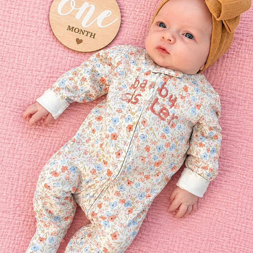 Rowyn joined the competition — help win amazing prizes! baby, infant, newborn, portrait, lying_down, pink_blanket, floral_outfit, headband, bow, milestone, one_month, wooden_sign, face, eyes, hands, feet, indoor, baby_photography, sleepwear, pastel