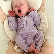 Rowyn is registered to the contest to win money with this photo: baby, newborn, infant, yawning, sleepy, portrait, indoors, lavender_clothing, unicorn_pattern, onesie, mittens, cushion, blanket, bed, soft_bedding, lying_down, stretching, baby_feet, cozy, cute