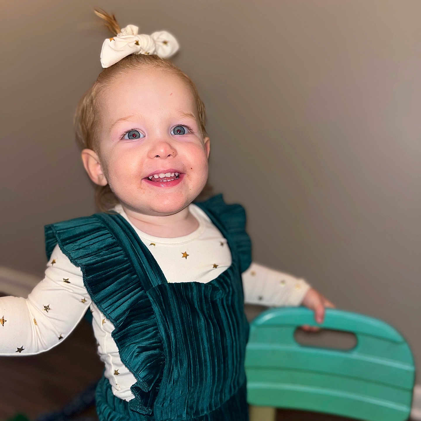 Iris is registered to the contest to win money with this photo: accessories, baby, babylaughing, bodypart, clothing, costume, dress, face, formalwear, happy, head, laughing, mouth, person, photography, portrait, sitting, smile, teeth, wood