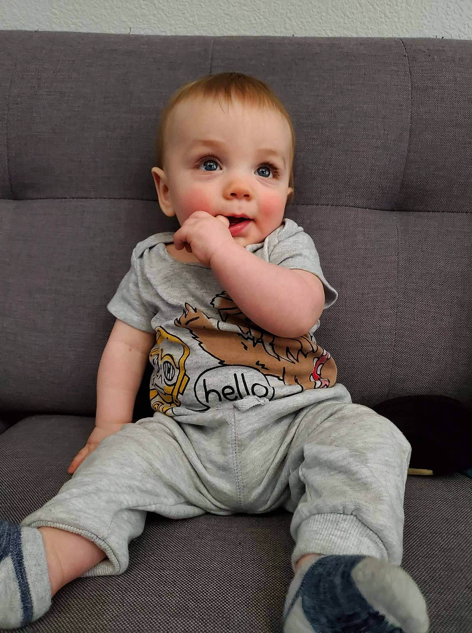 Mark is registered to the contest to win money with this photo: baby, baby_toddler_clothing, cheek, child, comfort, couch, eye, flooring, head, knee, living_room, pattern, person, product, sitting, sleeve, smile, sofa_bed, studio_couch, t_shirt