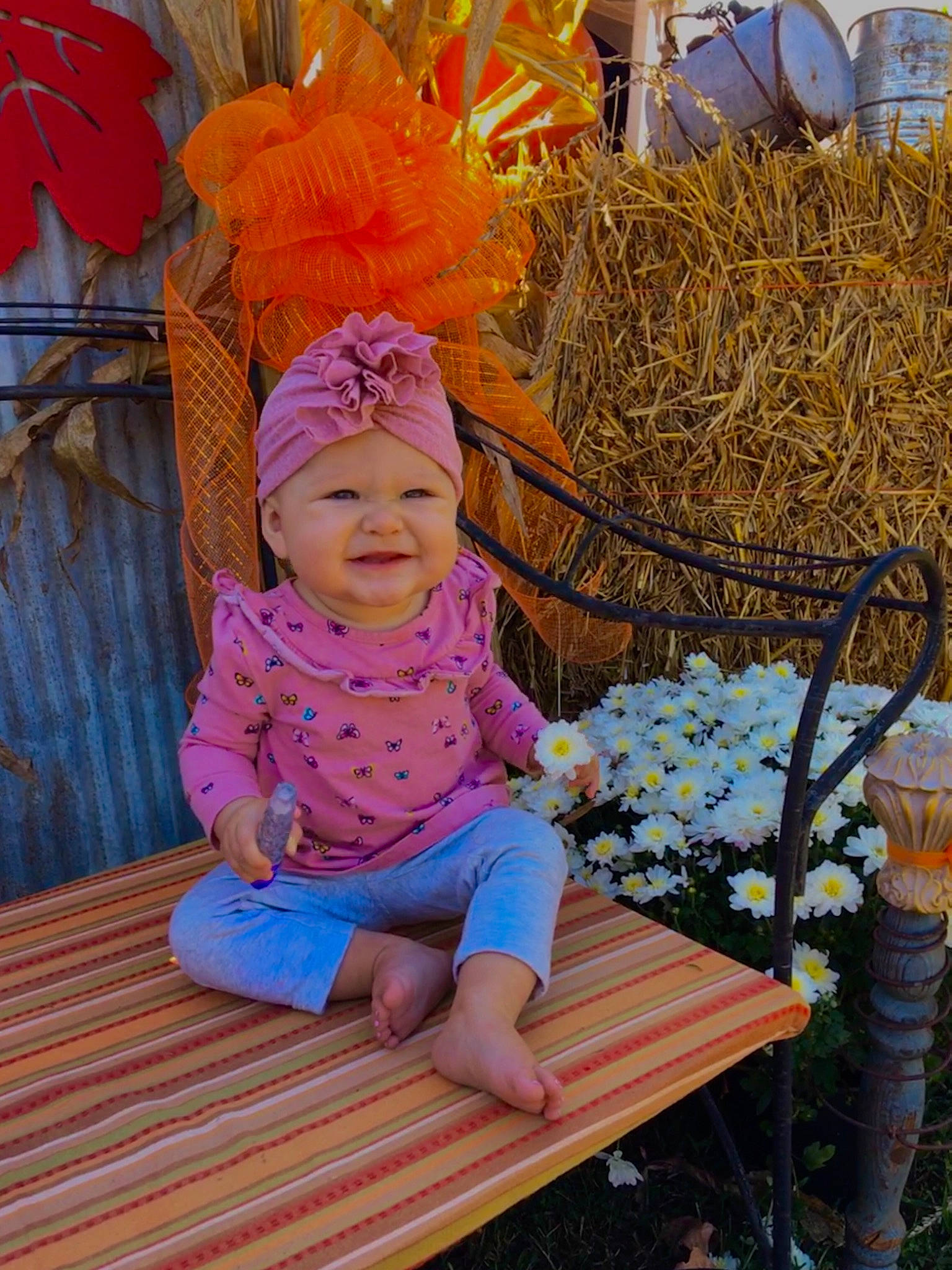 Lisa is registered to the contest to win money with this photo: agriculture, baby, baby_toddler_clothing, barefoot, bench, bouquet, costume_accessory, flower_arranging, flowerpot, foot, hay, headband, headwear, joy, mouth, nose, outdoor_bench, outdoor_furniture, person, straw