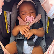 Hope Mulan is registered to the contest to win money with this photo: baby, car_seat, pacifier, headband, sleeping, infant, child, seatbelt, pink, gray, hands, clothing, cute, closeup, transport, safety, toddler, resting, indoors, peaceful
