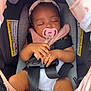 baby, car_seat, pacifier, headband, sleeping, infant, child, seatbelt, pink, gray, hands, clothing, cute, closeup, transport, safety, toddler, resting, indoors, peaceful