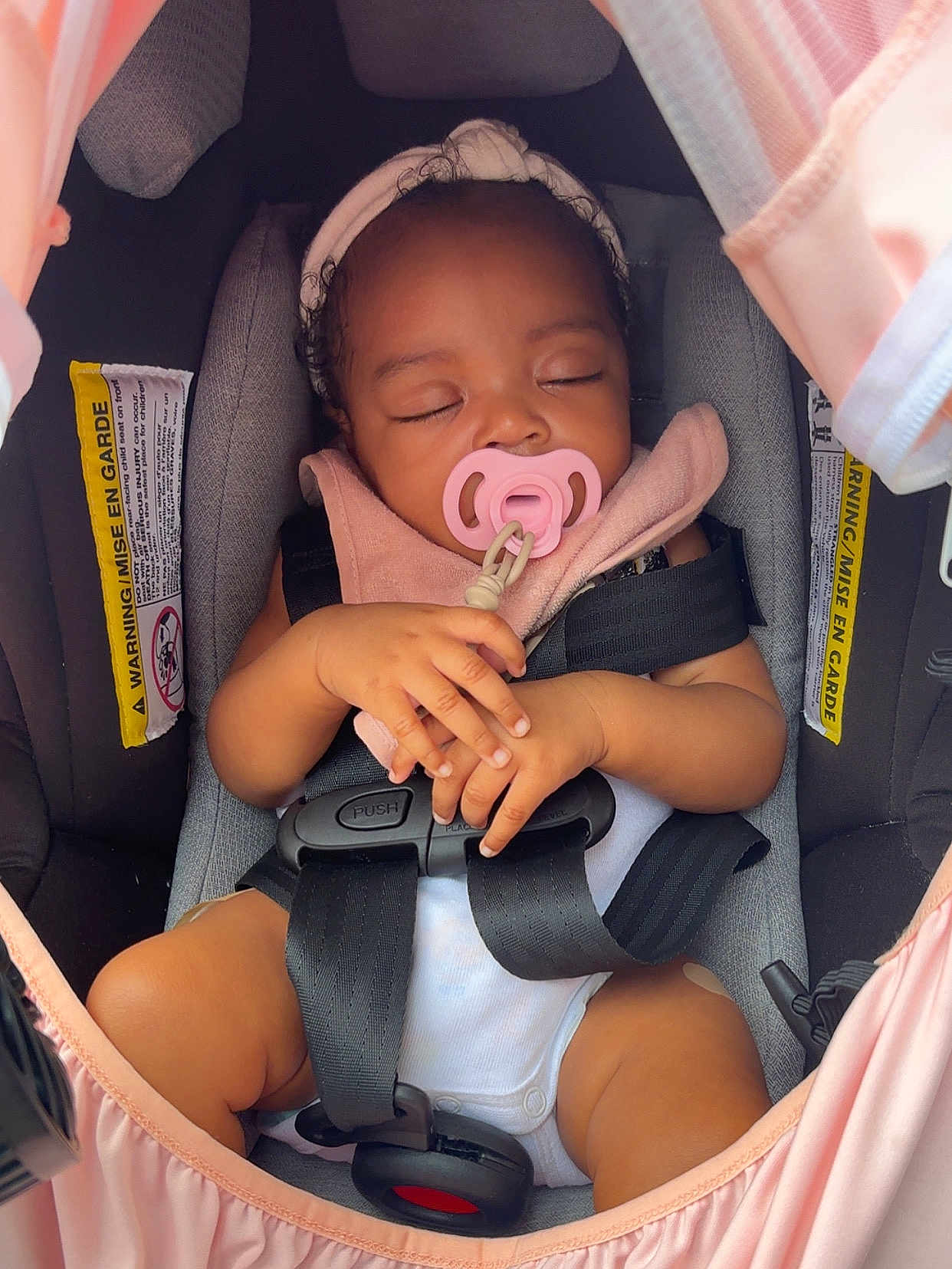 Hope Mulan is registered to the contest to win money with this photo: baby, car_seat, pacifier, headband, sleeping, infant, child, seatbelt, pink, gray, hands, clothing, cute, closeup, transport, safety, toddler, resting, indoors, peaceful