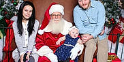 Ellie is registered to the contest to win money with this photo: baby, child, santa_claus, christmas_tree, christmas_decorations, red_carpet, gift_box, family, holiday, festive, woman, man, hat, boots, dress, chair, smile, indoor, portrait, glasses