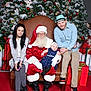 baby, child, santa_claus, christmas_tree, christmas_decorations, red_carpet, gift_box, family, holiday, festive, woman, man, hat, boots, dress, chair, smile, indoor, portrait, glasses