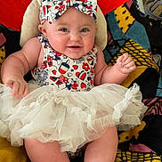 Ellie is registered to the contest to win money with this photo: baby, blanket, bow, cheeks, child, colorful, cute, fabric, feet, hands, happy, headband, indoor, infant, patterned_clothing, person, portrait, sitting, smiling, tutu