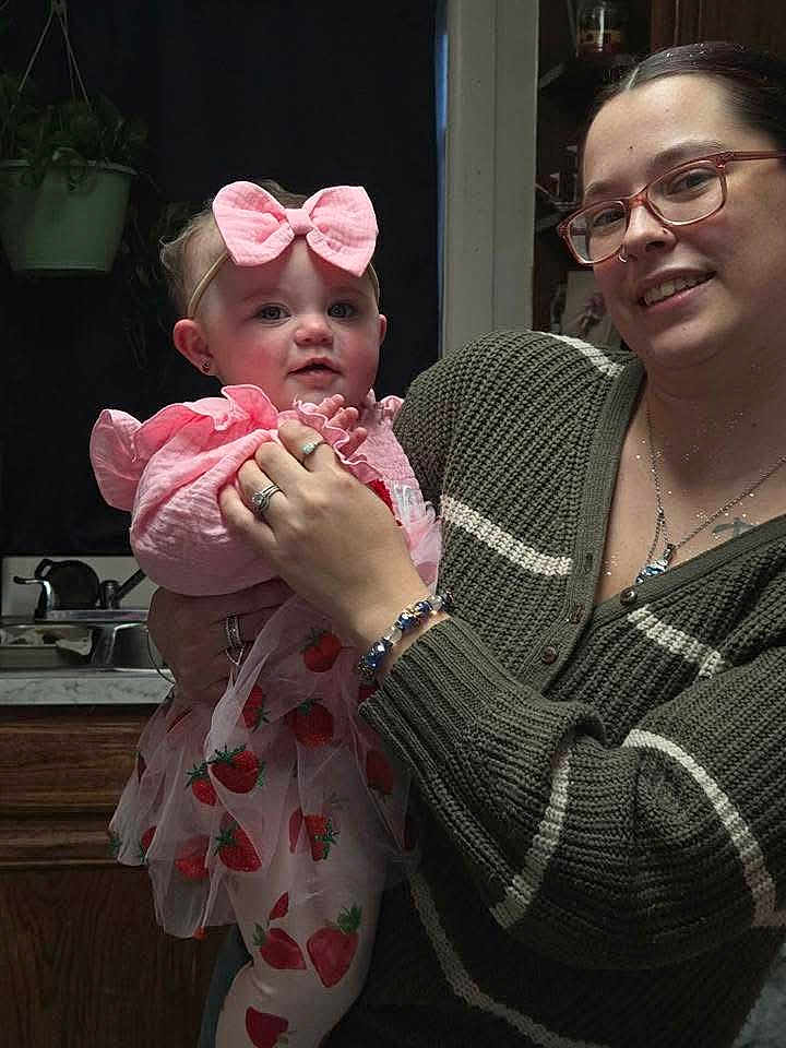 Ellie joined the competition — help win amazing prizes! baby, child, woman, glasses, pink_bow, strawberry_dress, kitchen, holding, smile, person, indoor, sweater, rings, bracelet, marble_countertop, sink, plant, cabinet, portrait, family