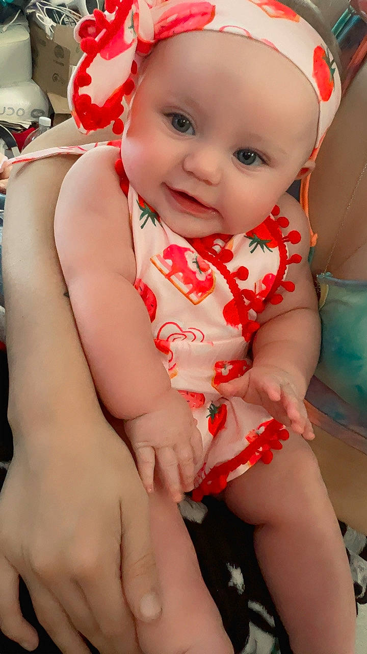 adorable, arm, baby, child, closeup, clothing, colorful, cute, expression, face, hand, headband, holding, indoor, infant, patterned_clothing, person, seated, skin, smile