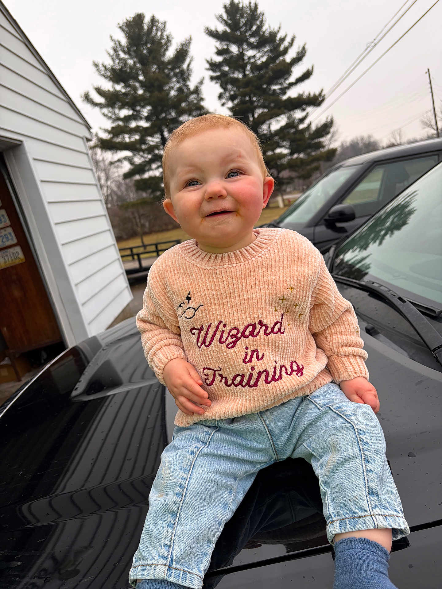 Octavia joined the competition — help win amazing prizes! child, toddler, baby, sweater, wizard_in_training, jeans, car, hood, outdoor, trees, overcast, smile, sitting, portrait, rosy_cheeks, playful, casual_clothing, candid, one_person, front_view