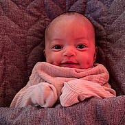 Rumi joined the competition — help win amazing prizes! baby, blanket, child, clothing, cozy, cute, dimples, face, happy, indoors, infant, portrait, quilt, resting, small_hands, smile, soft, textile, warm_lighting, wrapped