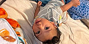 Xavier is registered to the contest to win money with this photo: child, baby, bed, blanket, pillow, clothing, hoodie, cartoon, face, smile, indoor, person, cute, cozy, fabric, soft, playful, curly_hair, toddler, resting
