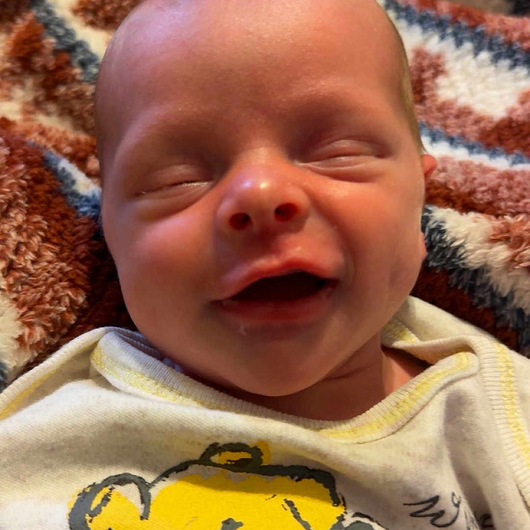 Bolin is registered to the contest to win money with this photo: baby, newborn, smiling, infant, face, clothing, tshirt, cartoon, winnie_the_pooh, blanket, pattern, happy, cute, child, resting, indoors, portrait, closeup, skin, head
