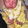 Bolin is registered to the contest to win money with this photo: baby, sleeping, yellow_pajamas, bib, winnie_the_pooh, person, infant, child, cute, hand, face, clothing, pattern, soft_lighting, indoor, human, resting, newborn, toddler, holding