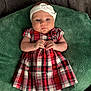 Emela joined the competition — help win amazing prizes! baby, infant, child, plaid_dress, headband, green_cushion, white_tights, hands, face, portrait, cute, indoors, soft_texture, clothing, pattern, expression, young, sitting, resting, person