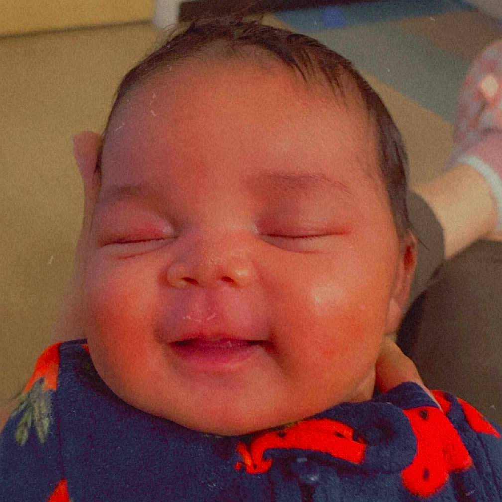 Shayonna joined the competition — help win amazing prizes! baby, infant, sleeping, smiling, strawberry_print, onesie, child, cute, face, happy, indoor, person, newborn, cozy, soft_lighting, hand, portrait, resting, head, peaceful