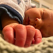Thomas participe au concours pour gagner de l'argent avec cette photo : baby, newborn, sleeping, infant, hand, fingers, close_up, blanket, onesie, sleeve, soft_texture, cozy, peaceful, portrait, indoor, bed, face, pinky, macro, shallow_depth_of_field