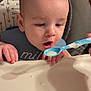 Dayton Jr is registered to the contest to win money with this photo: baby, infant, highchair, spoon, paper_plate, bib, feeding, drooling, hands, food, closeup, portrait, indoor, caregiver_hand, surprised_expression, face, head, seated, tray, patterned_background