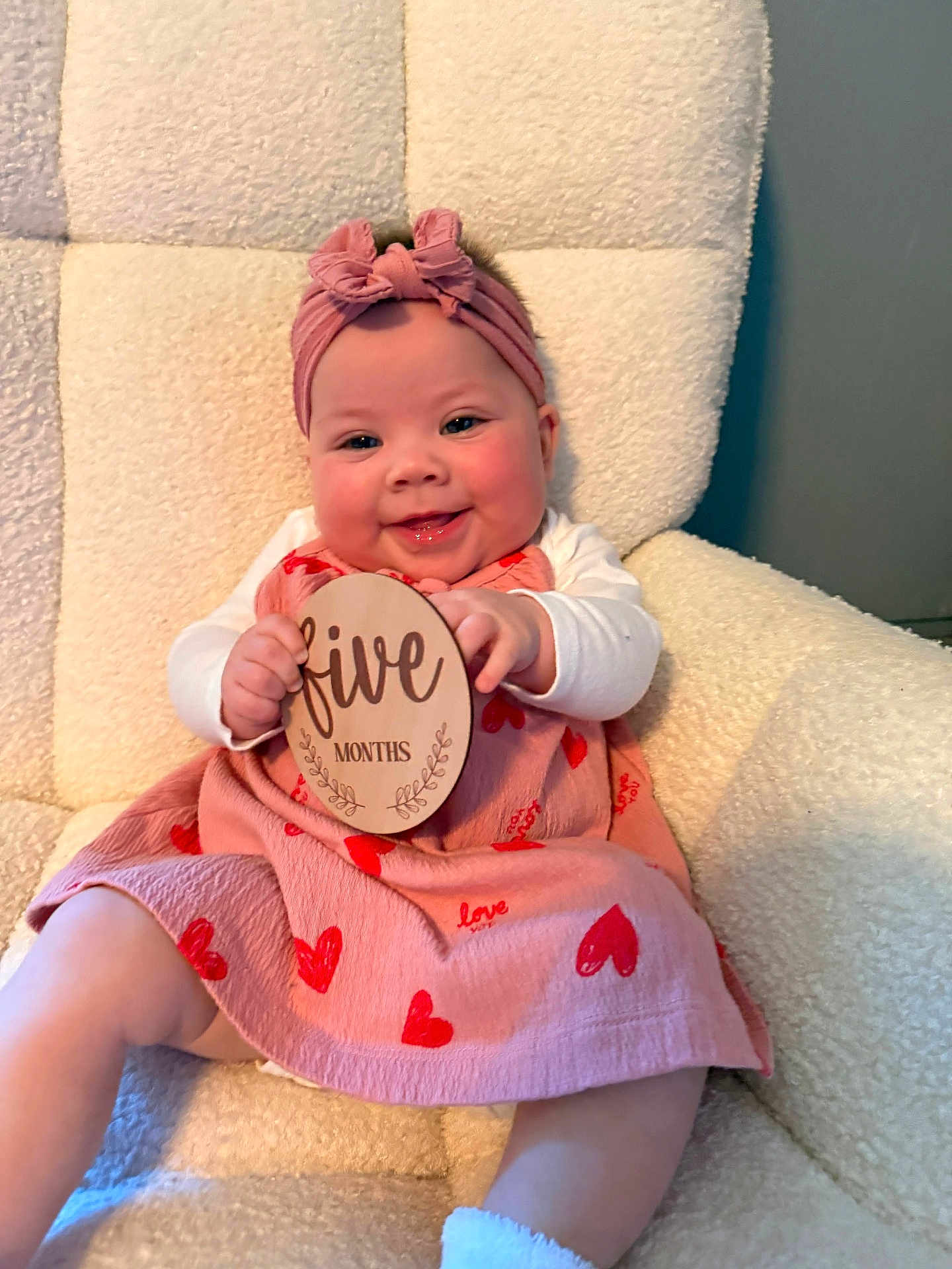 Kaizley is registered to the contest to win money with this photo: baby, chair, child, comfortable, cute, dress, five_months, happy, headband, hearts, indoors, infant, milestone, person, plush, portrait, sign, sitting, smiling, wooden_sign