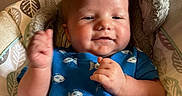 Felix is registered to the contest to win money with this photo: baby, child, infant, smiling, happy, portrait, sitting, bouncer, baby_seat, blue_clothing, patterned_clothing, raised_hand, indoor, home, cushion, safety_harness, furniture, warm_lighting, close_up, photography