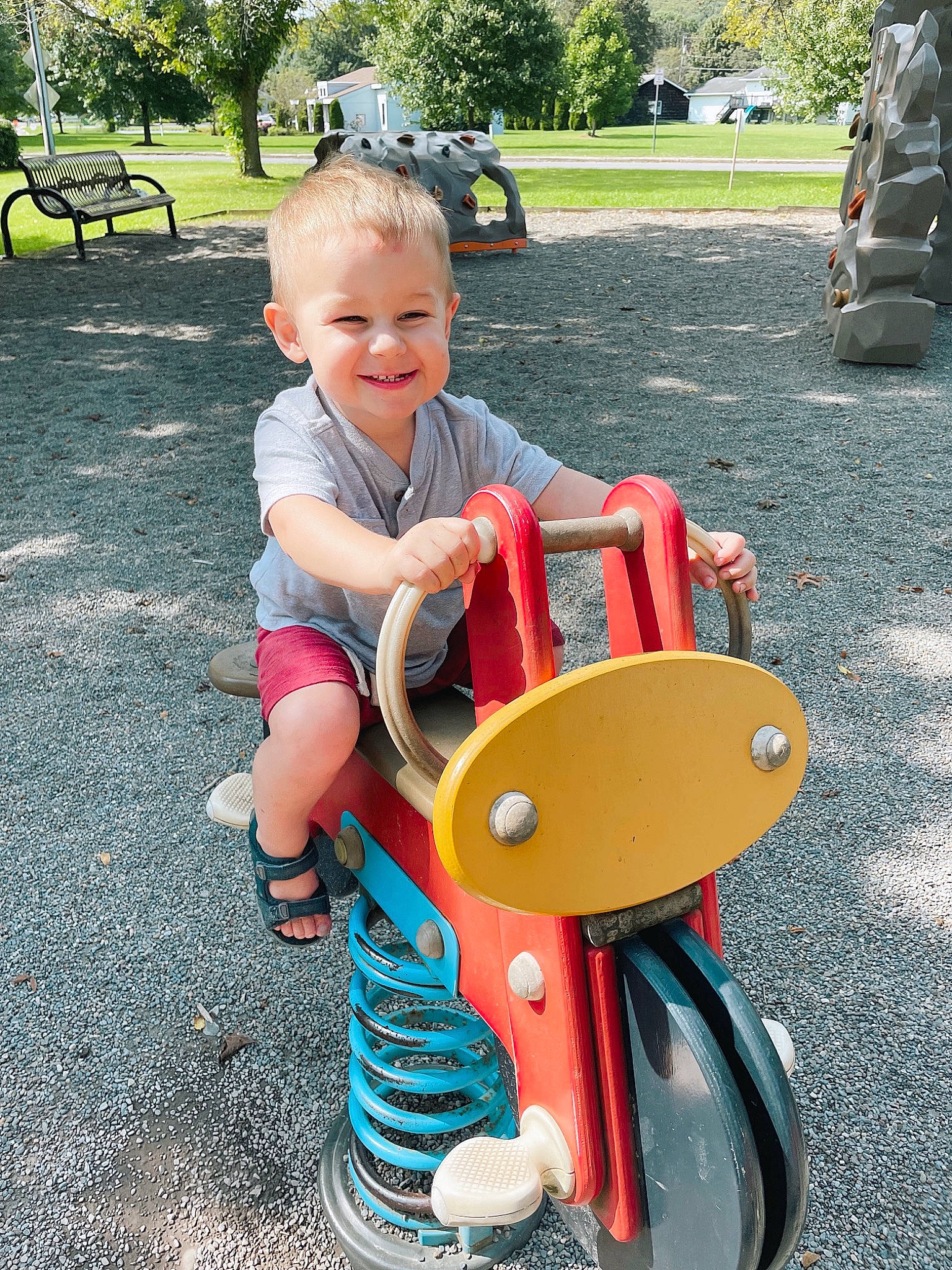 Princeton is registered to the contest to win money with this photo: asphalt, baby, baby_toddler_clothing, child, city, fun, grass, joy, leisure, person, photograph, plant, public_space, recreation, riding_toy, sitting, smile, snapshot, tire, toddler